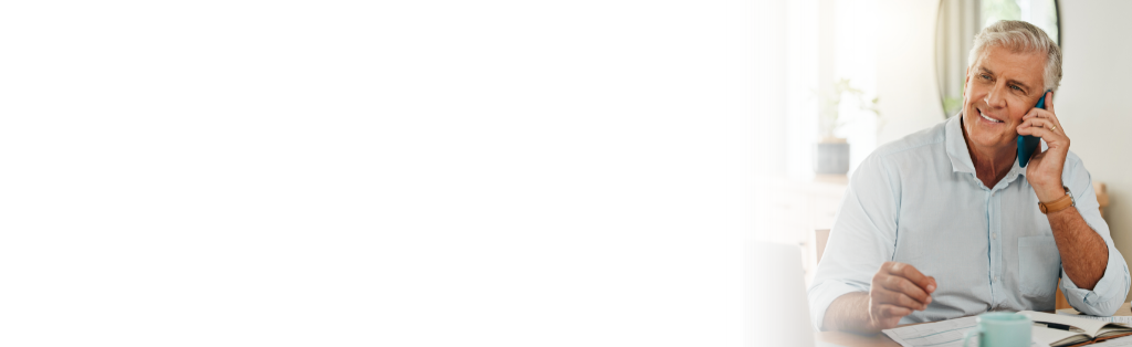 An older man sitting at a desk and talking on the phone