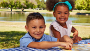 Two kids sitting at a table at the park